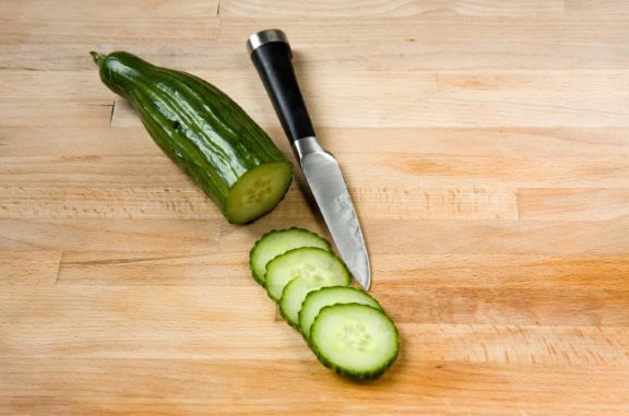 A cutting board with sliced cucumbers on it.