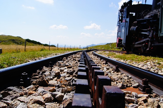 An open rail track going off into the distances beside an old steam engine